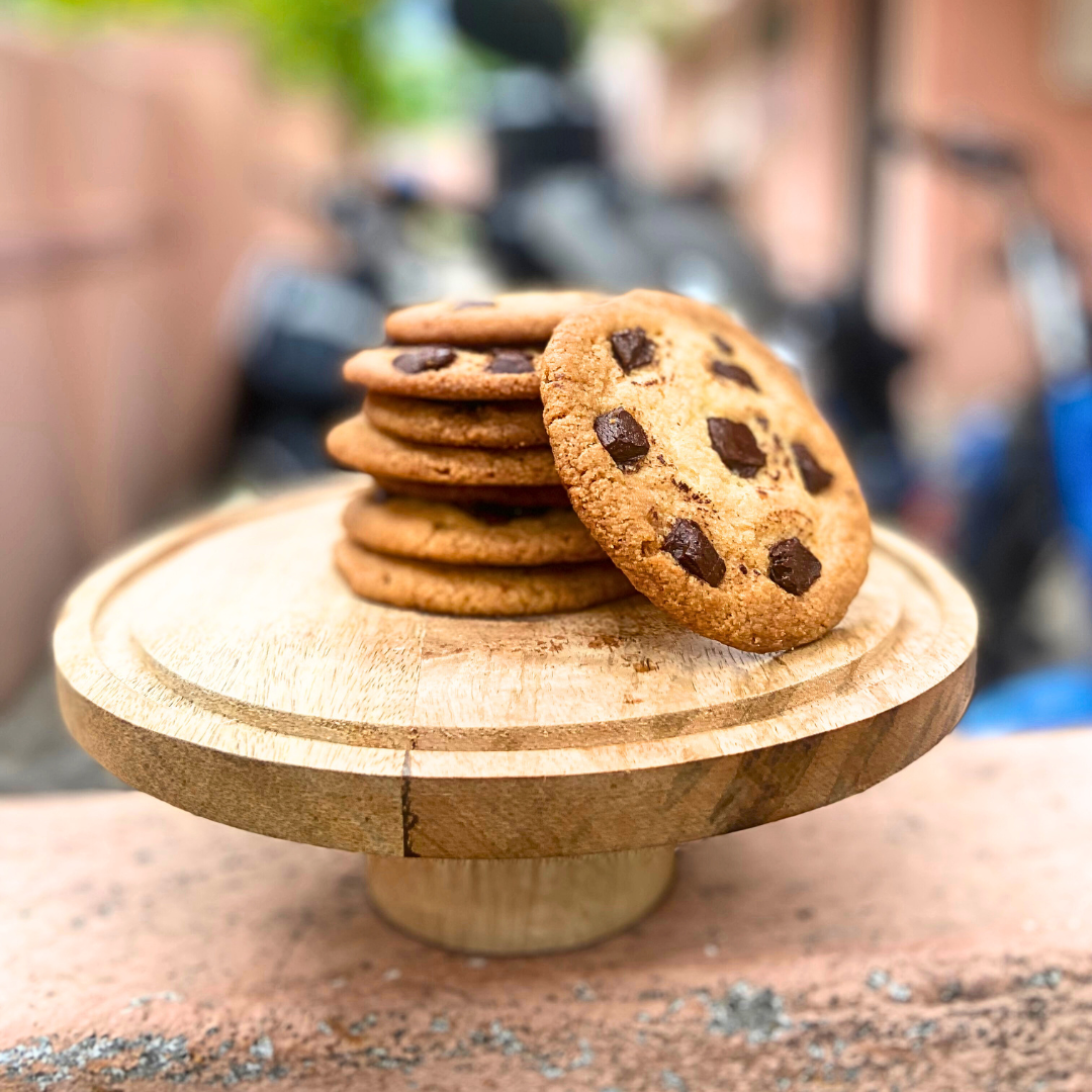 Golden brown chocolate chip cookies stacked on a plate.