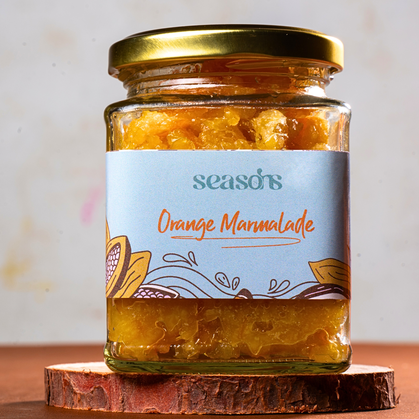 Glass jar of golden-orange marmalade with fresh oranges in the background.