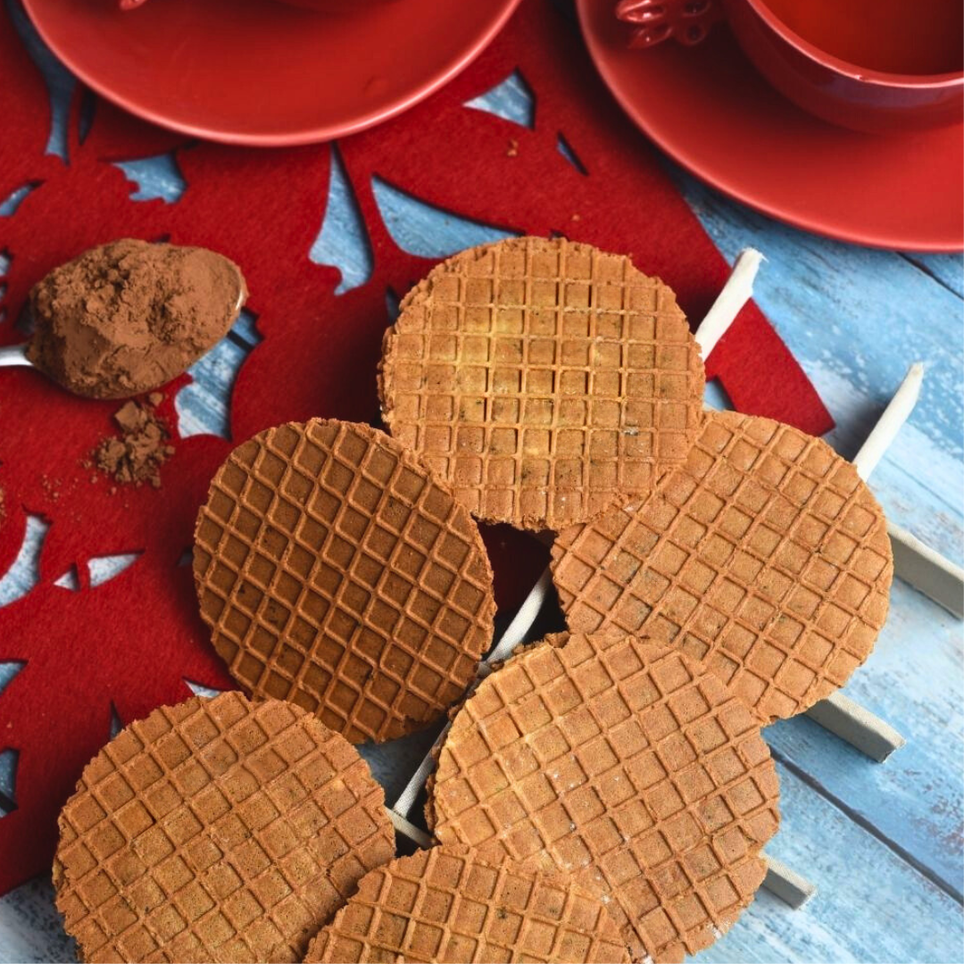 Chocolate-dipped waffle thins with a bite taken, revealing a crispy texture.